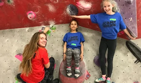 Children and an instructor beside an indoor climbing wall