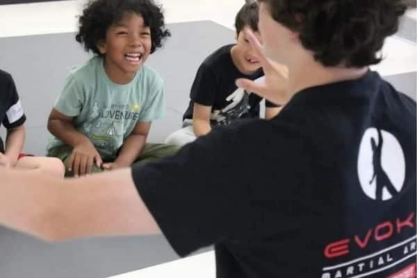 Children laugh with an Evoke martial arts instructor