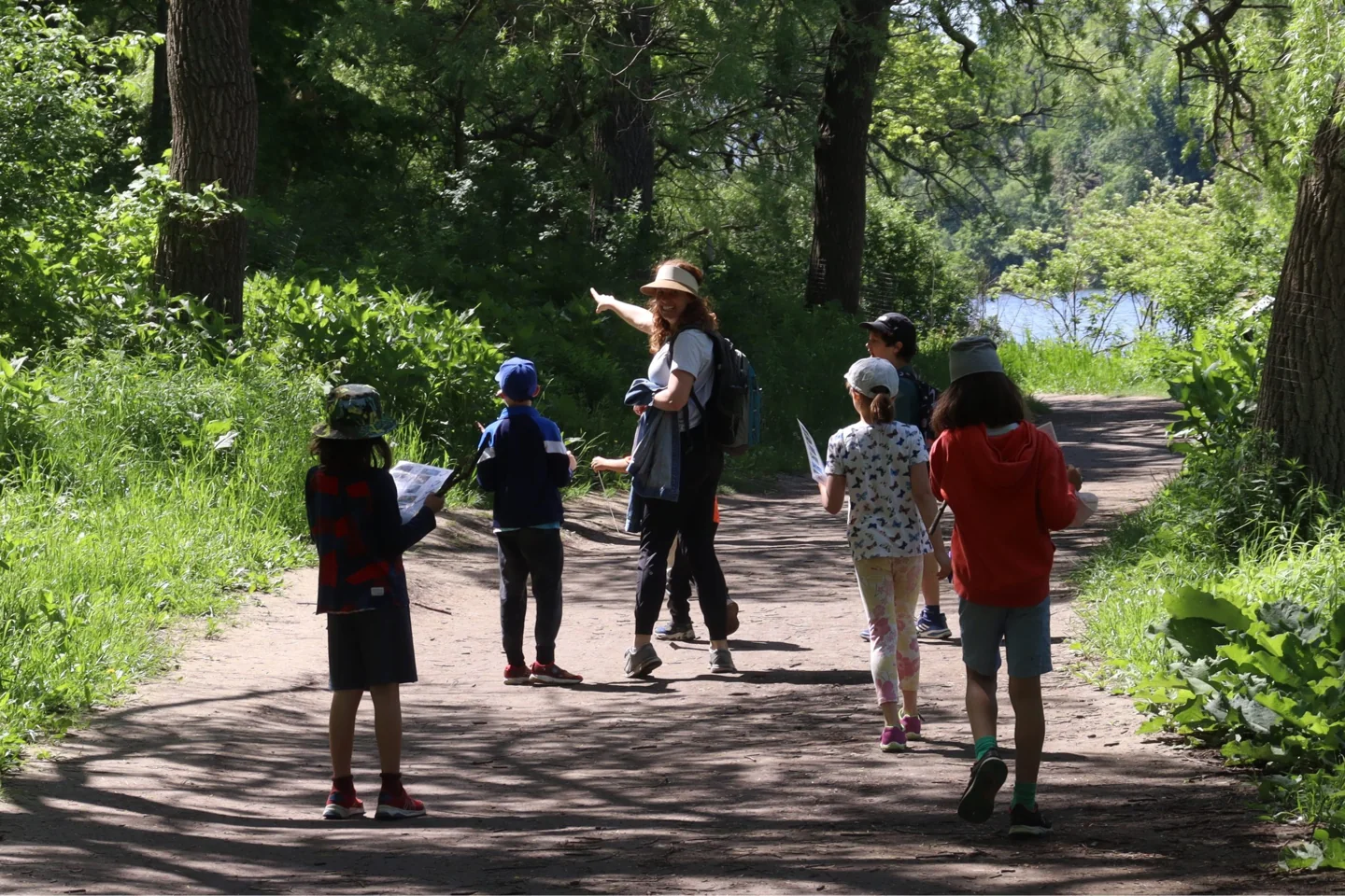 Children and an instructor walk on a tree-lined High Park path