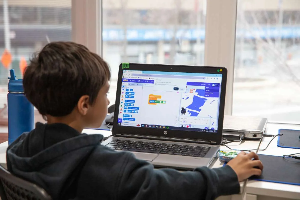 A child uses coding blocks on a laptop in a MakerKids class