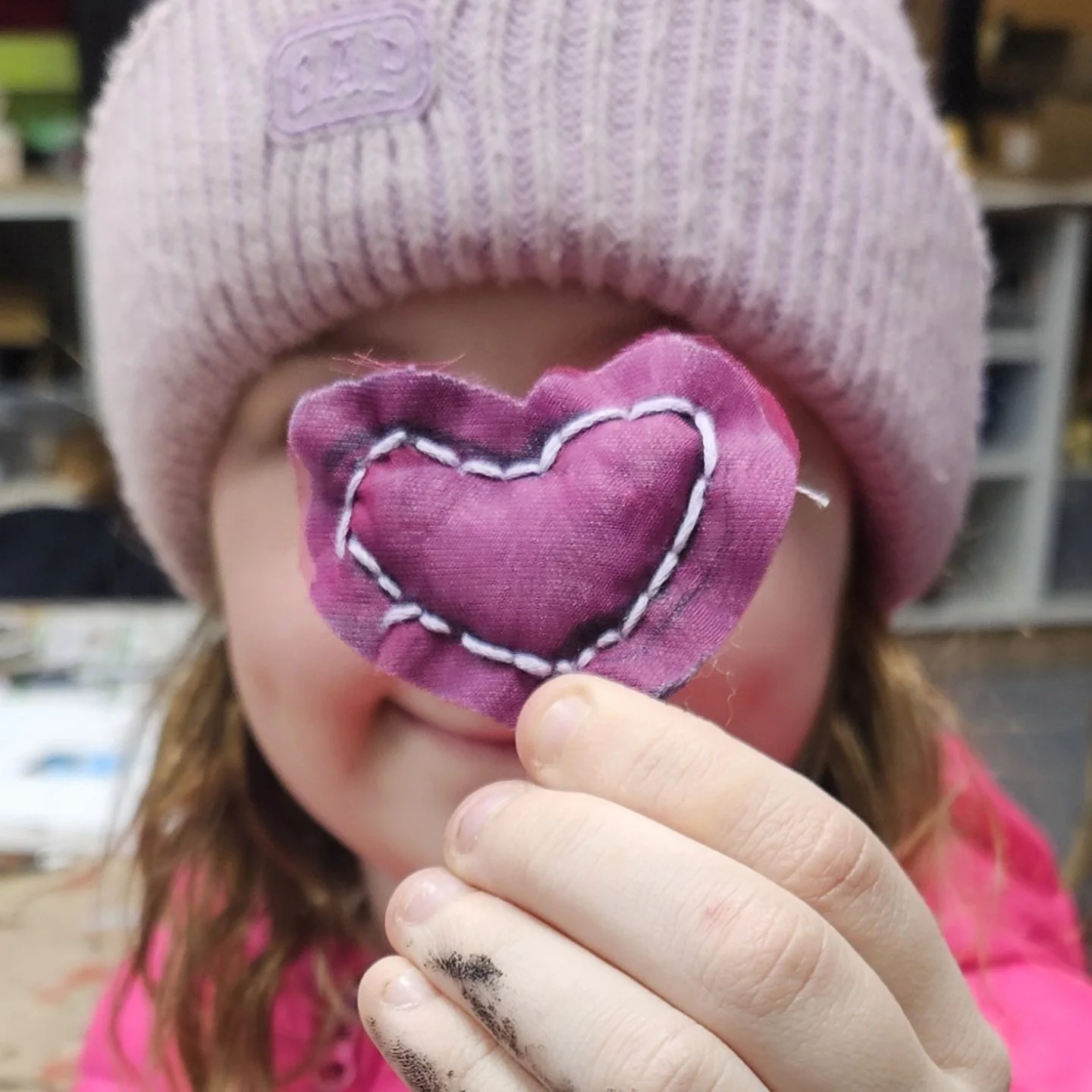 A child holds a handmade fabric heart at Mischief Makers