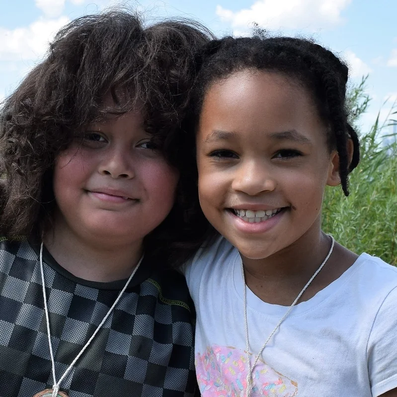 Two children smile together during an outdoor camp