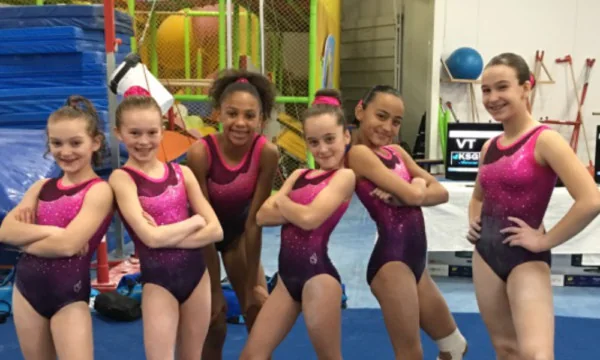 Young gymnasts pose together inside the Toronto Gymnastics International gym