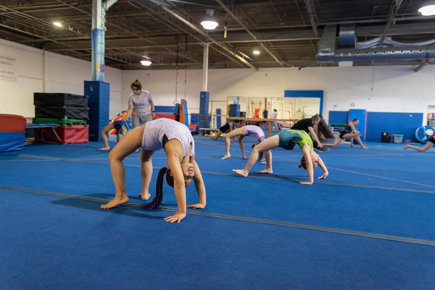 Children practise gymnastics on a blue gym floor