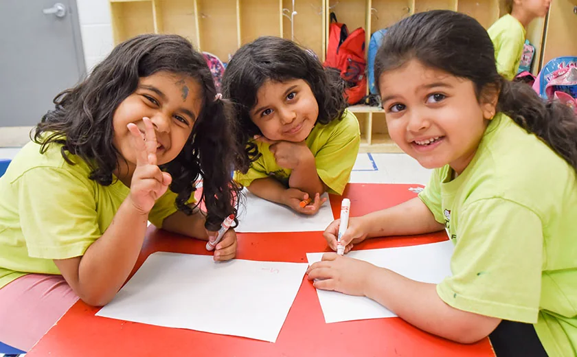 Children draw together at a table during a University Settlement programme