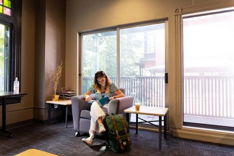 A student reading beside a window in the Innis Commuter Lounge