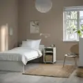 A bright small bedroom with a single bed and simple furniture