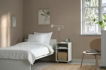 A bright small bedroom with a single bed and simple furniture