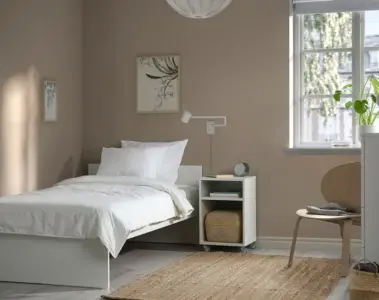 A bright small bedroom with a single bed and simple furniture