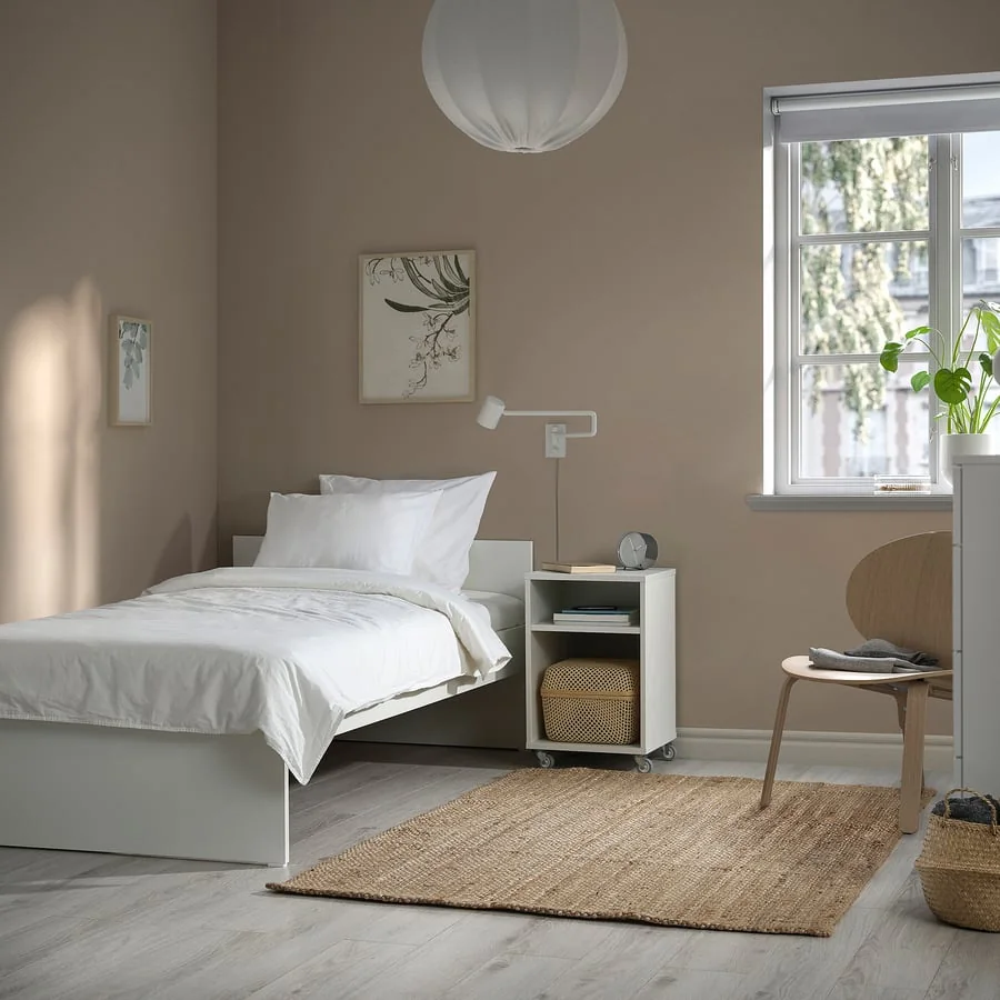 A bright small bedroom with a single bed and simple furniture