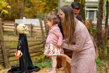 A woman and small child beside a Halloween display at the Village at Black Creek