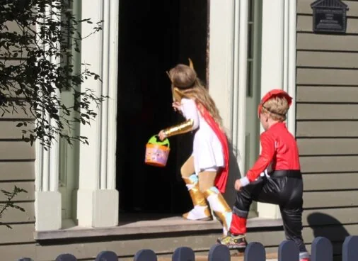 Children in costumes visiting a Black Creek building in daylight
