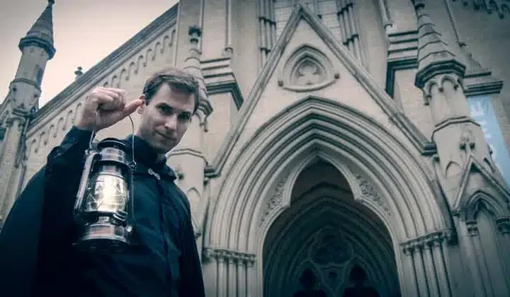 A Haunted Walk guide holding a lantern outside a Toronto church