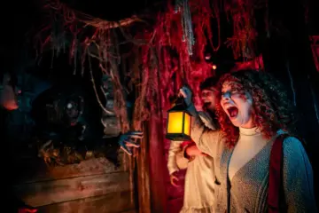 A woman holding a lantern reacts to a Halloween scene