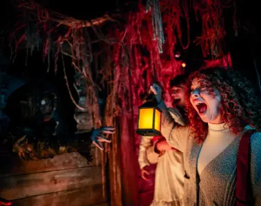 A woman holding a lantern reacts to a Halloween scene