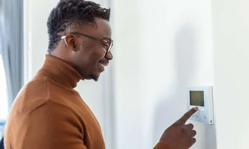 A man checks a wall thermostat.