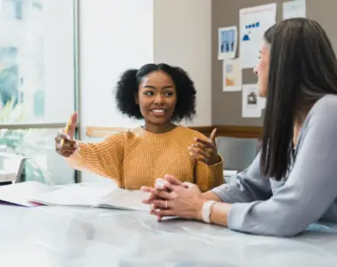 Two students talking at a table on campus