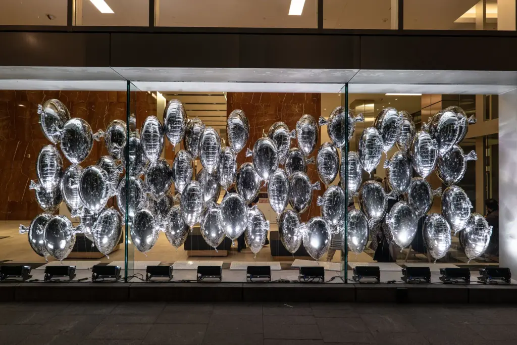 Silver balloons displayed behind windows in the 2022 waterfront Avataq installation