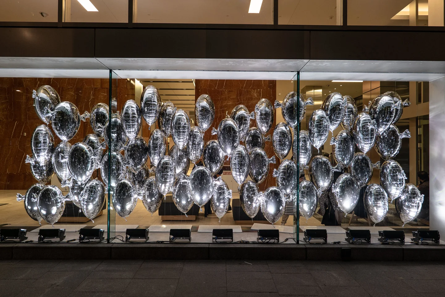 Silver balloons displayed behind windows in the 2022 waterfront Avataq installation