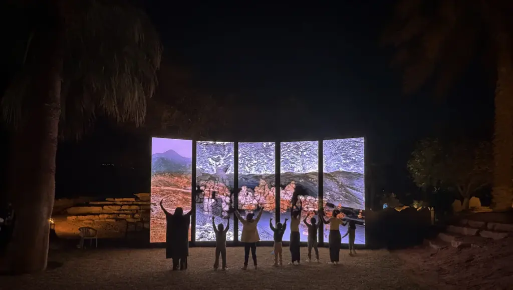 Visitors standing before illuminated panels showing water and landscapes