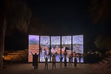 Visitors standing before illuminated panels showing water and landscapes