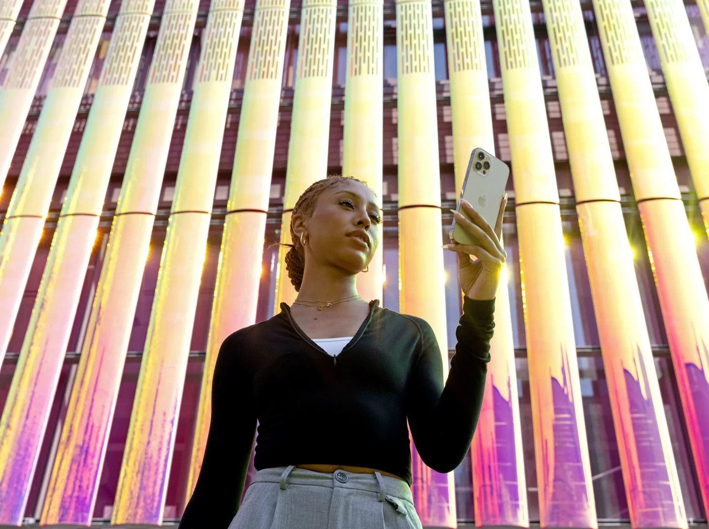 A student holding her phone beside colourful columns.