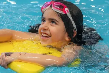 A girl swimming with a kickboard.