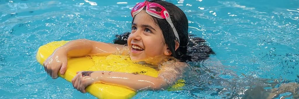 A girl swimming with a kickboard.