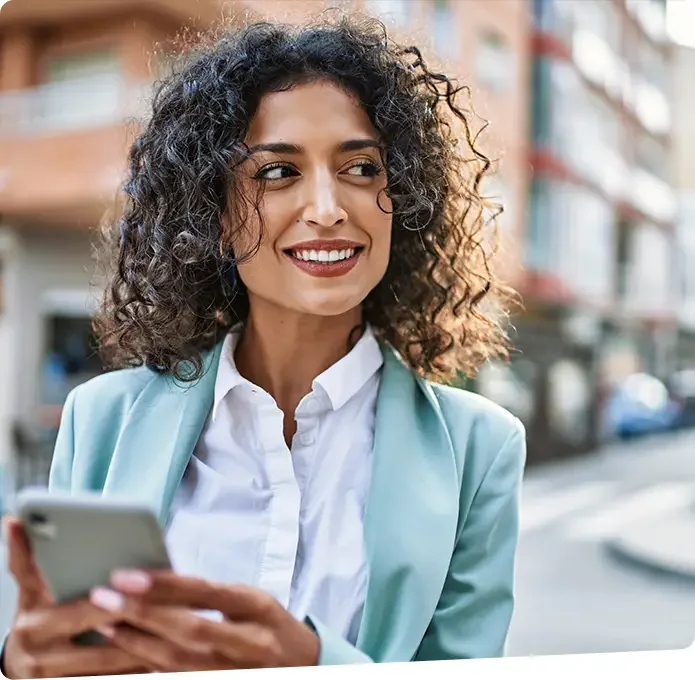 A business woman is smiling while looking away from her phone.