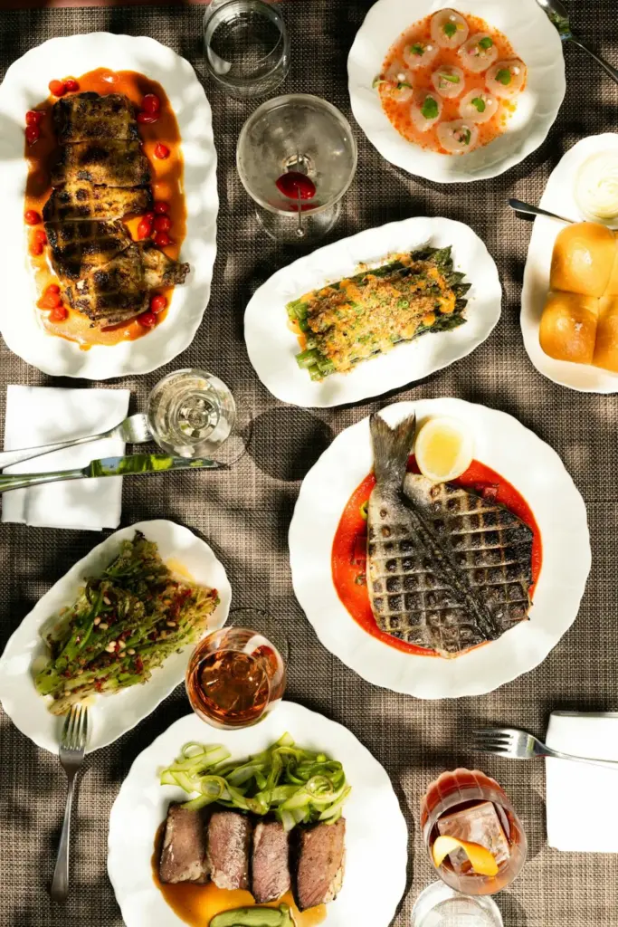 A table of plated dishes and shared sides at Alder
