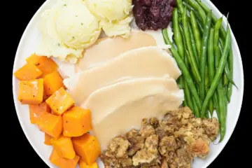Turkey, gravy, stuffing, potatoes, beans and squash on a plate