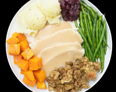 Turkey, gravy, stuffing, potatoes, beans and squash on a plate