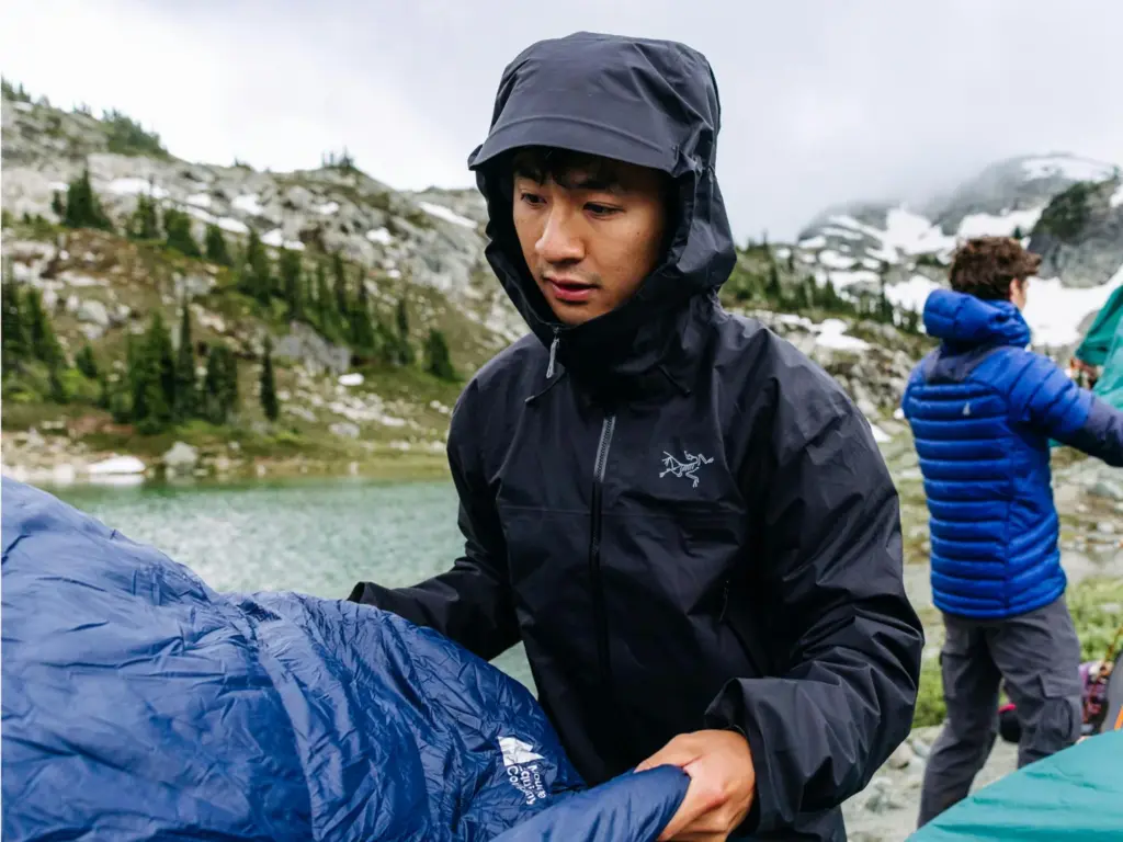 Person wearing a rain shell with the hood raised