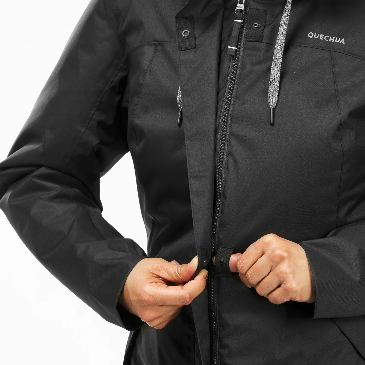 Hands closing the front of a black winter jacket