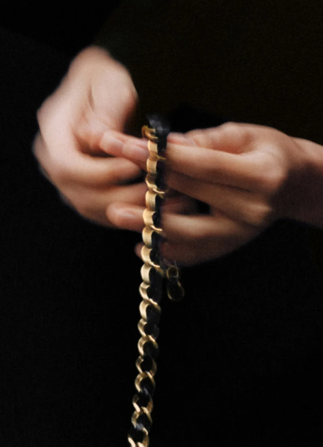 Hands work on a handbag chain in a Chanel atelier