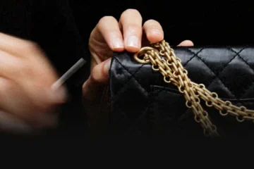 Hands work on a black quilted Chanel handbag