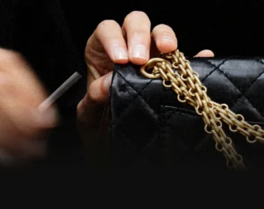 Hands work on a black quilted Chanel handbag