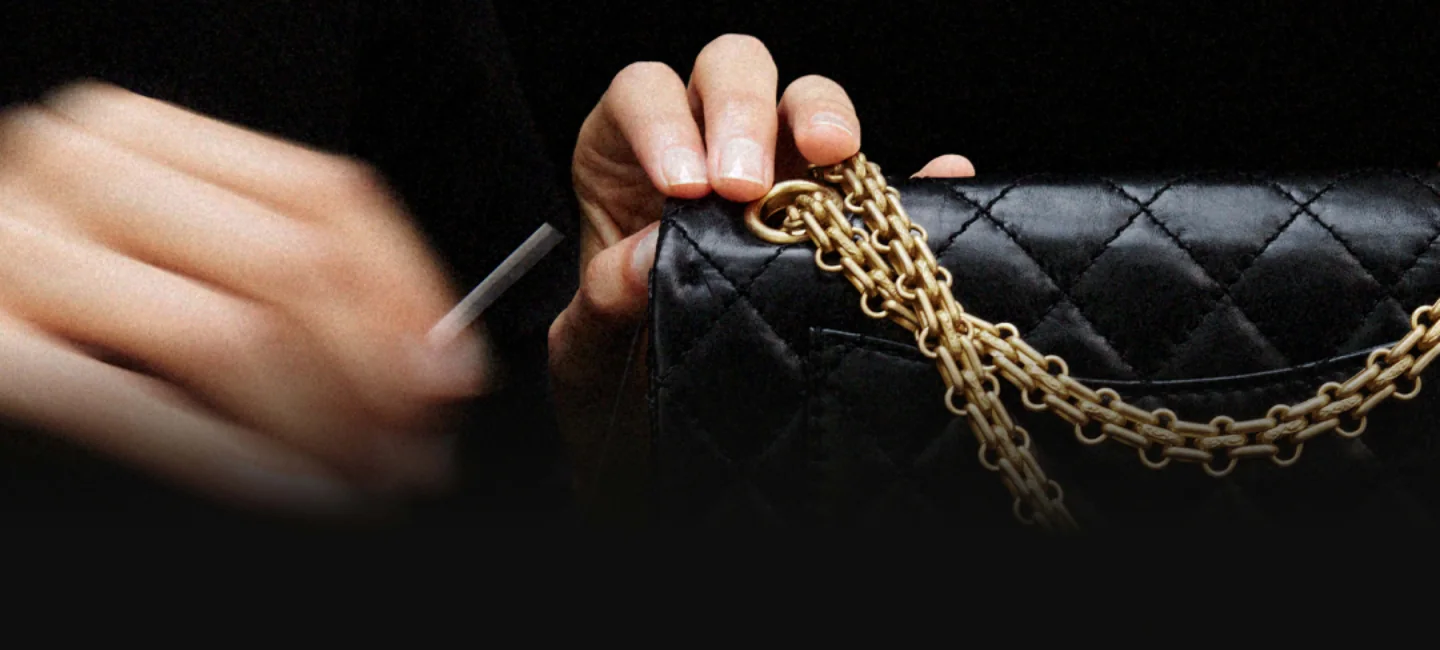 Hands work on a black quilted Chanel handbag
