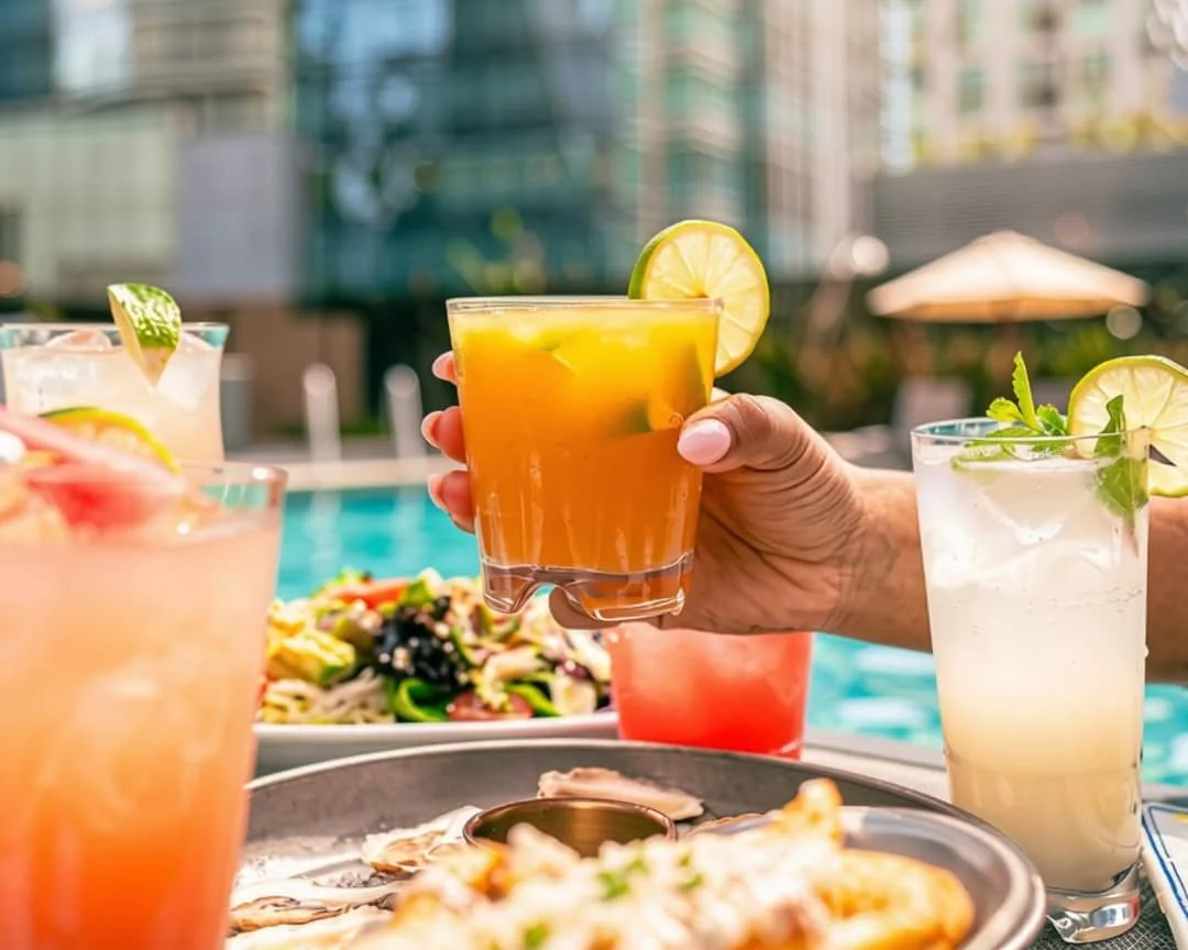 A guest holds a cocktail beside food and other drinks in Hilton Toronto’s promotional photograph