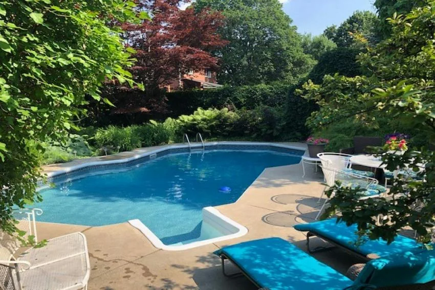 A private outdoor pool surrounded by plants and a wooden deck