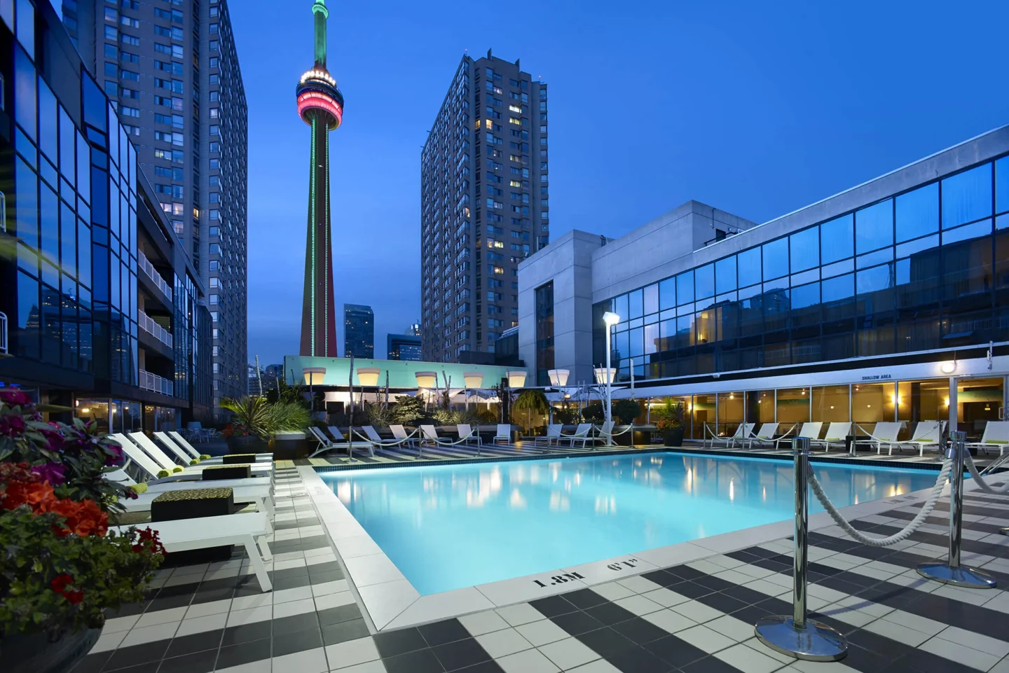 Radisson Blu Toronto’s pool and lounge at dusk with the CN Tower behind it