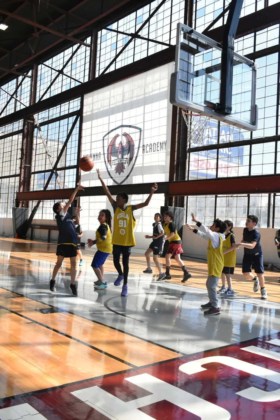 Young basketball players practise below a hoop inside QSLA / Ballmatics