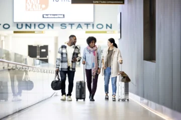 Three travellers with suitcases walk towards the UP Express terminal at Union Station