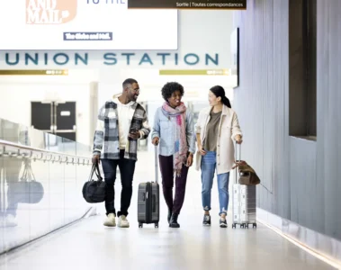 Three travellers with suitcases walk towards the UP Express terminal at Union Station