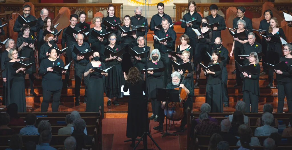 The Annex Singers perform with open music folders and a conductor