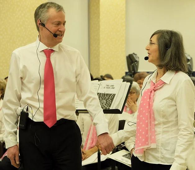 Two Choralairs singers perform with microphones and music stands