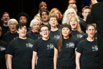 Singing Out members sing together in black choir T-shirts