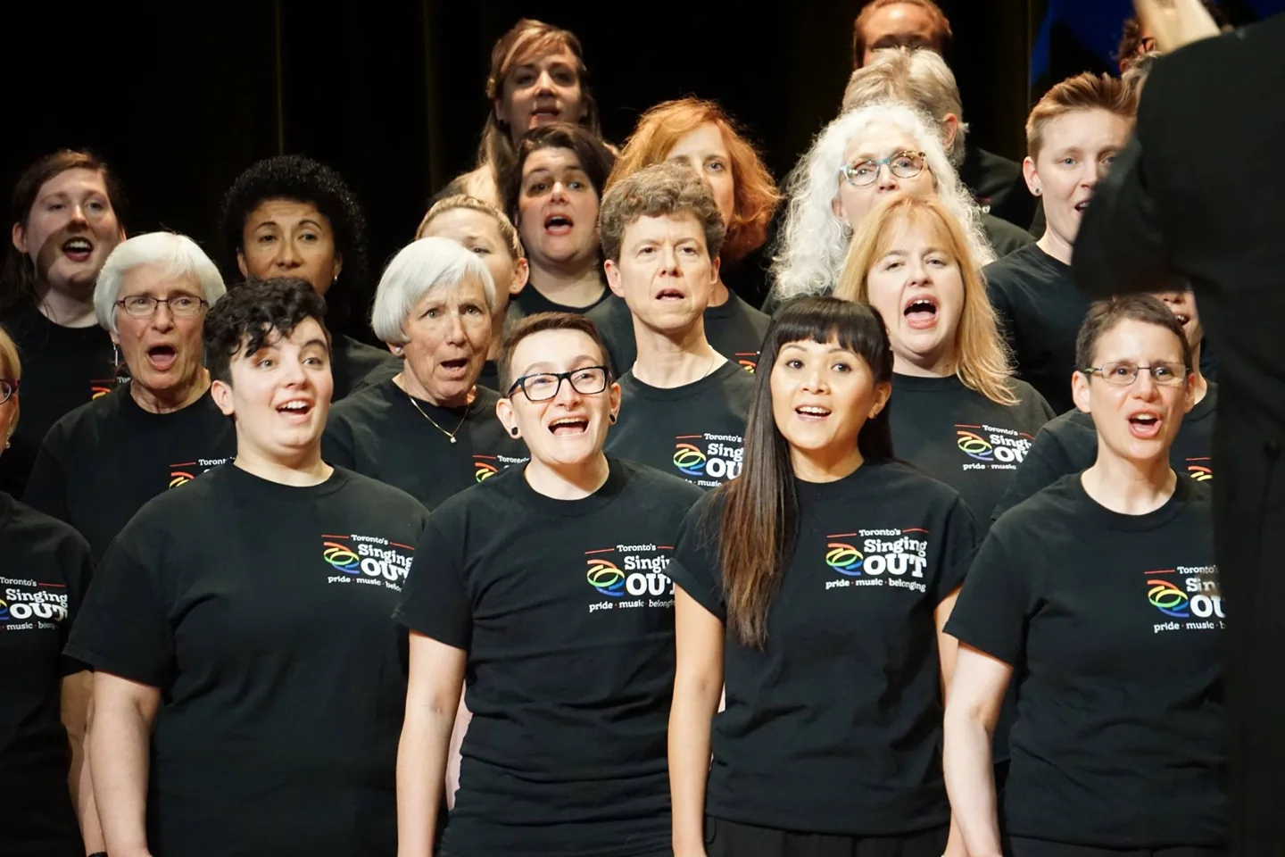 Singing Out members sing together in black choir T-shirts