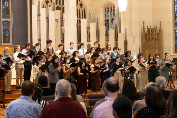 A Modern Sound Collective choir performs in a church while a conductor faces the singers