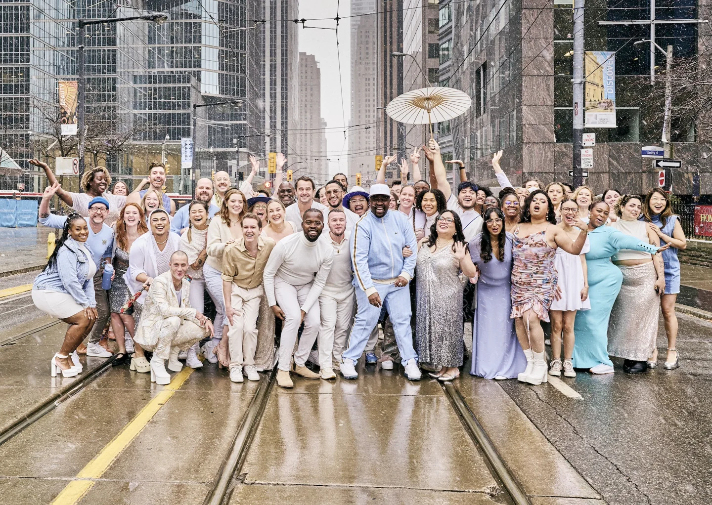 Inkloosiv Voices members in light-coloured clothing gather outdoors at The Well